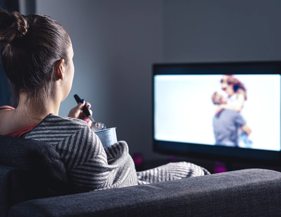 Mujer sentada en el sofá viendo una película mientras come helado