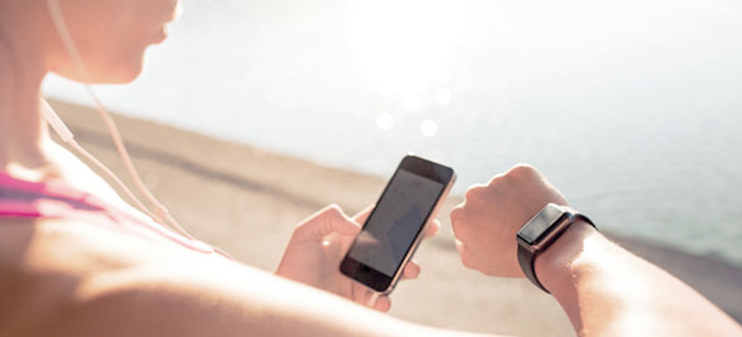 Mujer antes de correr sincronizando el móvil con su smart watch