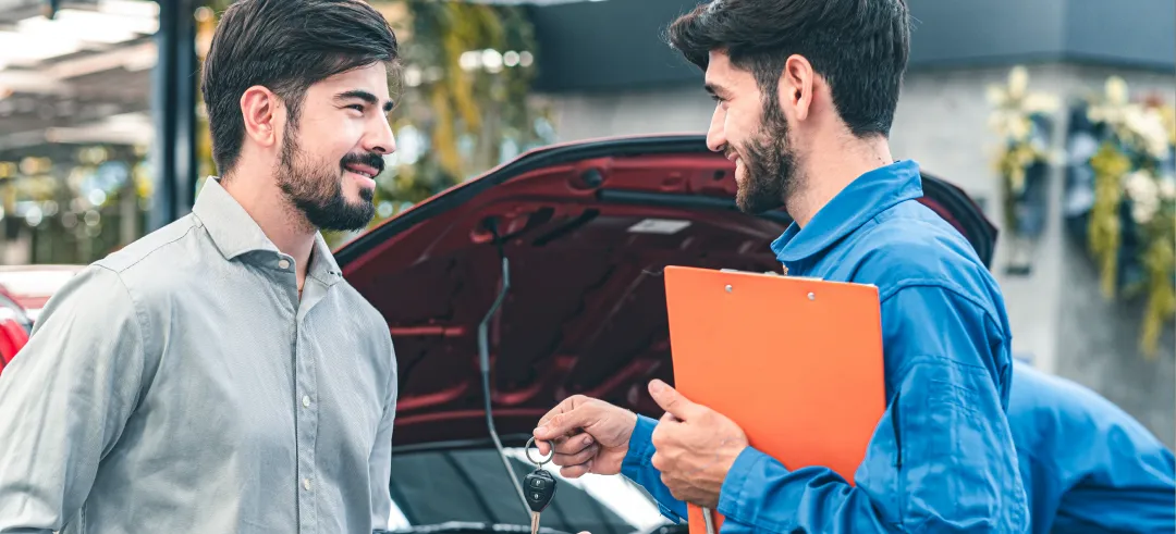 Mecánico dando las llaves de un coche a un hombre en un taller
