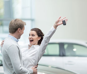 Pareja celebrando la compra de un coche en el concesionario